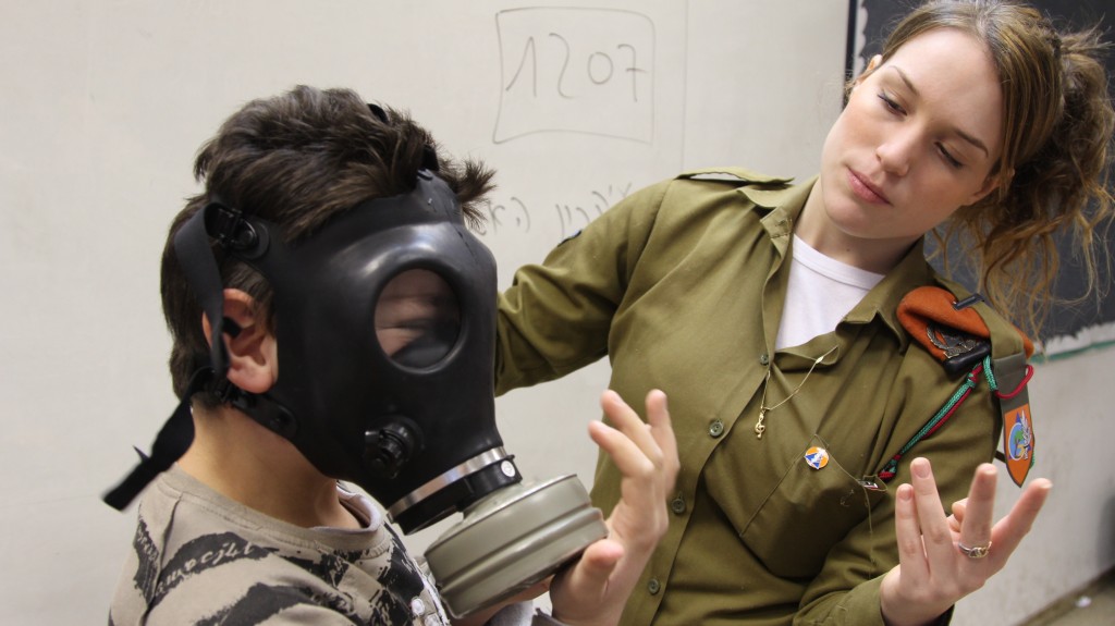 An IDF instructer teaches a child how to put on a gas mask in Holon. Photo: Israel Defense Forces / flickr