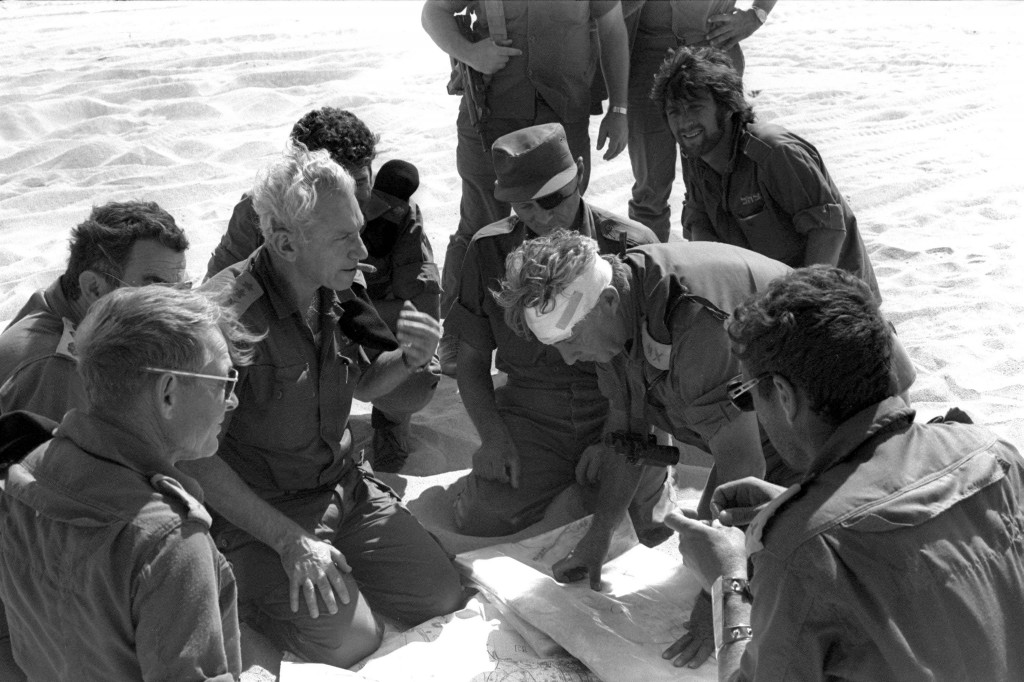 Haim Bar-Lev (center left), Moshe Dayan (with eyepatch), and Ariel Sharon (with head bandage) consult plans during the Yom Kippur War. Photo: Yossi Greenberg / GPO / Flash90