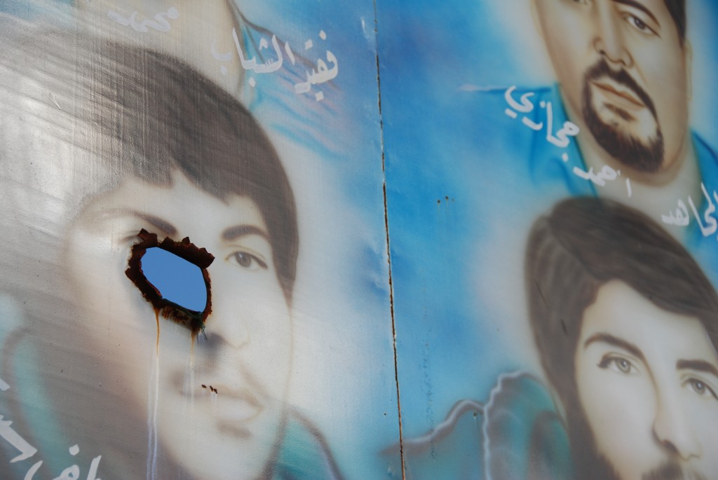 Shell hole in the portrait of a dead Hezbollah fighter painted on a signboard along the road from Tyre to Bint Jbeil in southern Lebanon. Photo: Paul Keller / flickr
