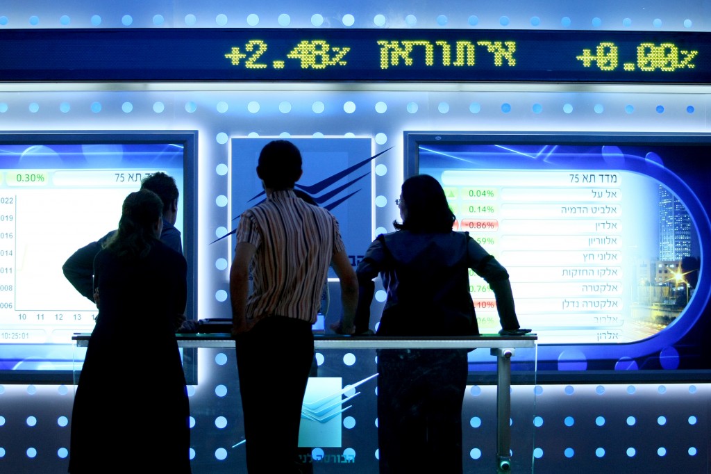 People watch a board showing stock fluctuations at the Tel Aviv stock exchange. Photo: Moshe Shai / Flash90