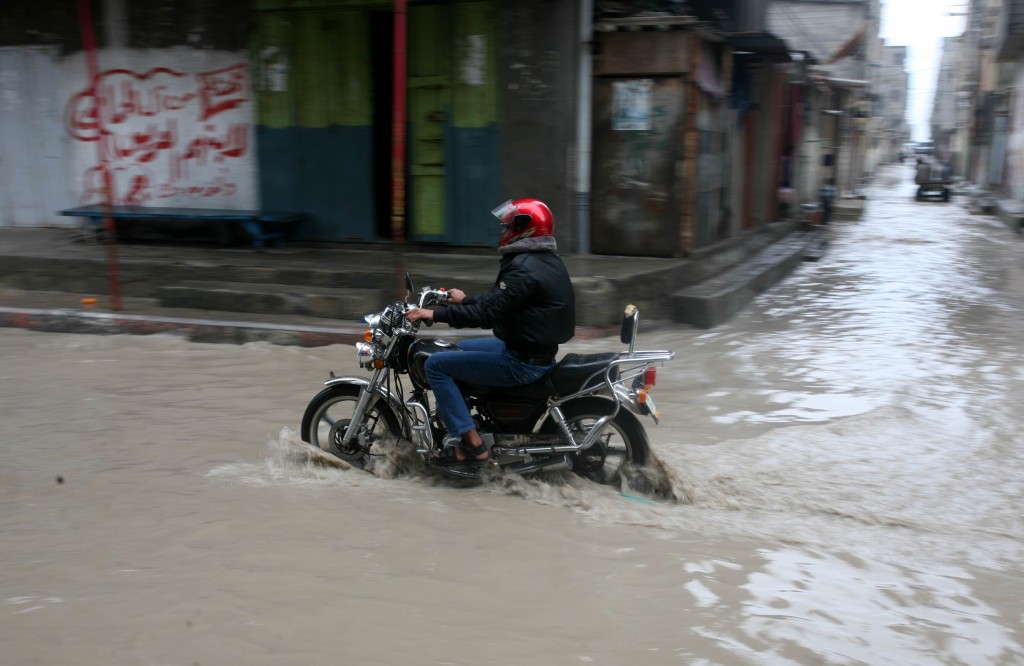 A Palestinian man rides his a bike through a flood in Gaza City. Photo: Mohammed Othman / Flash90