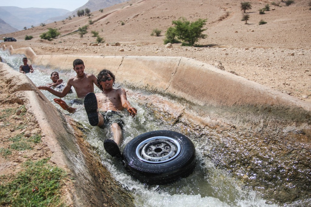 Palestinians playing in a running stream of channeled irrigation water to cool off, on a hot summer day in the West Bank city of Jericho, where the temperatures soared to 40 degrees. Photo: Issam Rimawi / Flash90