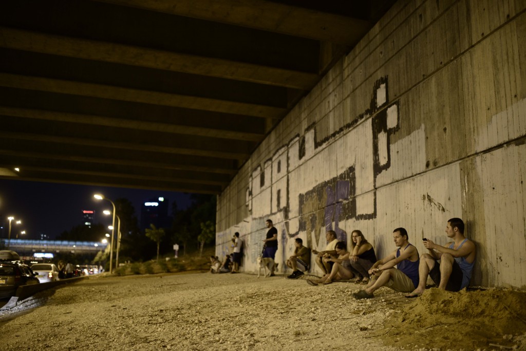Israelis in Tel Aviv take cover as a siren warns of incoming rockets. Photo: Tomer Neuberg / Flash90