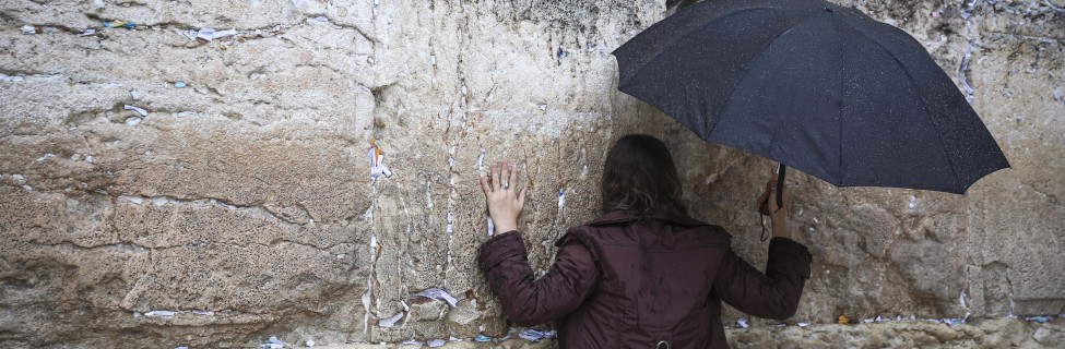 A Jewish woman prays at the Western Wall in Jerusalem's Old City while holding an umbrella during heavy rainfall, November 16, 2014. Photo: Hadas Parush / Flash90