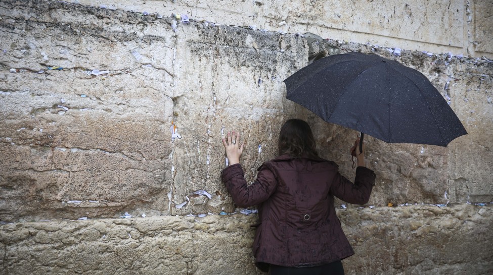 A Jewish woman prays at the Western Wall in Jerusalem's Old City while holding an umbrella during heavy rainfall, November 16, 2014. Photo: Hadas Parush / Flash90