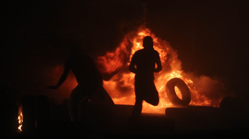 Palestinian men burn tires during clashes with Israeli border police at the Qalandiya checkpoint, between Jerusalem and Ramallah, late on July 24, 2014, following a massive march attended by 10,000 Palestinian protesters against Israel's military actions in the Gaza Strip. Photo: Issam Rimawi / Flash90