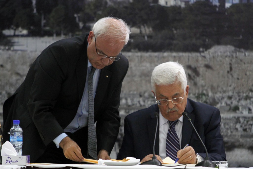 Palestinian Authority President Mahmoud Abbas (R)  signs applications to join 15 UN agencies as chief peace negotiator Saeb Erekat assists him, April 1, 2014. Photo: Issam Rimawi / Flash90
