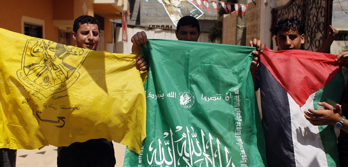 Palestinian protesters wave the flags of Palestinian political movements, Fatah (yellow) and Hamas (green) as they chant slogans in support of the national reconciliation and the announcement of the formation of a national unity government between the two factions, in Khan Yunis, in the southern Gaza Strip, on May 29, 2014. Palestinian premier Rami Hamdallah is to head the consensus government to be formed under a deal with Hamas to end seven years of rival administrations in the West Bank and Gaza, an official said. Photo by Abed Rahim Khatib/ Flash90 *** Local Caption *** òæä
øöåòú òæä
çîàñ
ôàúç
àéçåã
îîùìä