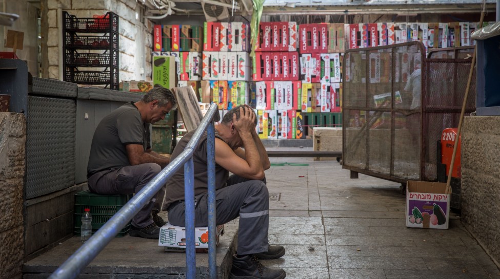 Workers sit in an alleyway at the nearly-empty Mahane Yehuda market in Jerusalem, October 15, 2015. Photo: Nati Shohat / Flash90