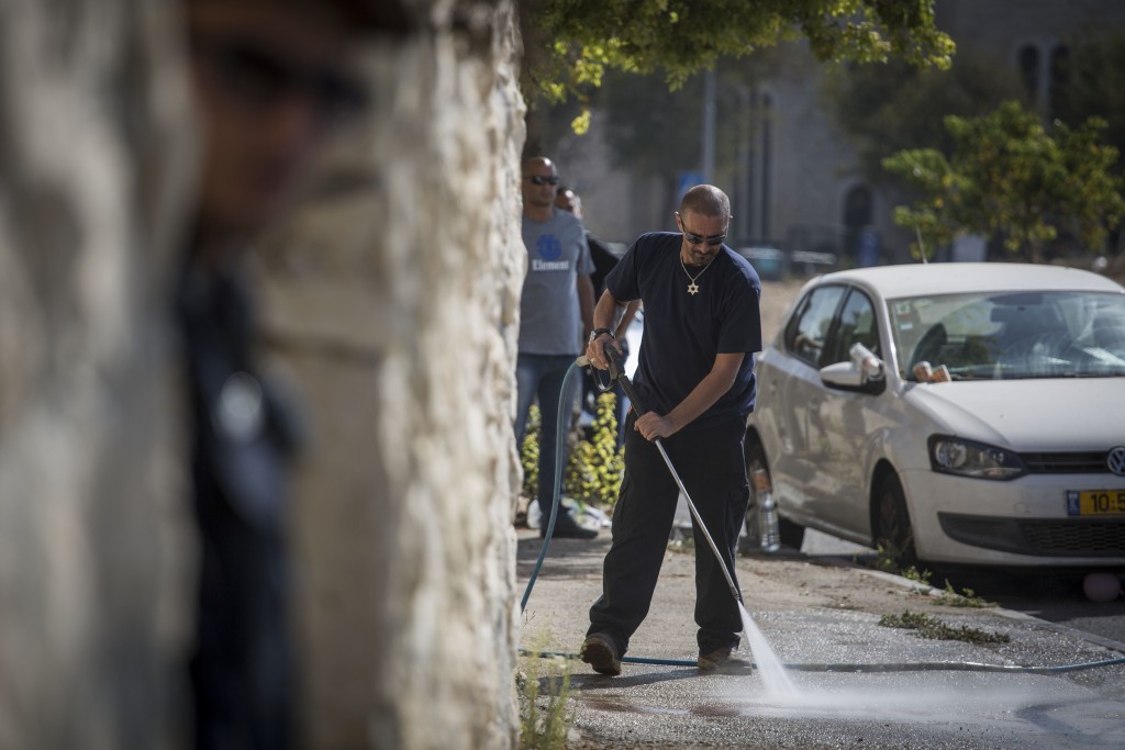 A sanitation worker cleans up the scene of an attempted stabbing attack in Jerusalem, October 17, 2015. Police were called to check on a suspicious-looking Arab man in the neighborhood of Armon Hanatziv. When they came to check his ID, he pulled out a knife, injuring a policeman before being shot and killed. Photo: Hadas Parush / Flash90