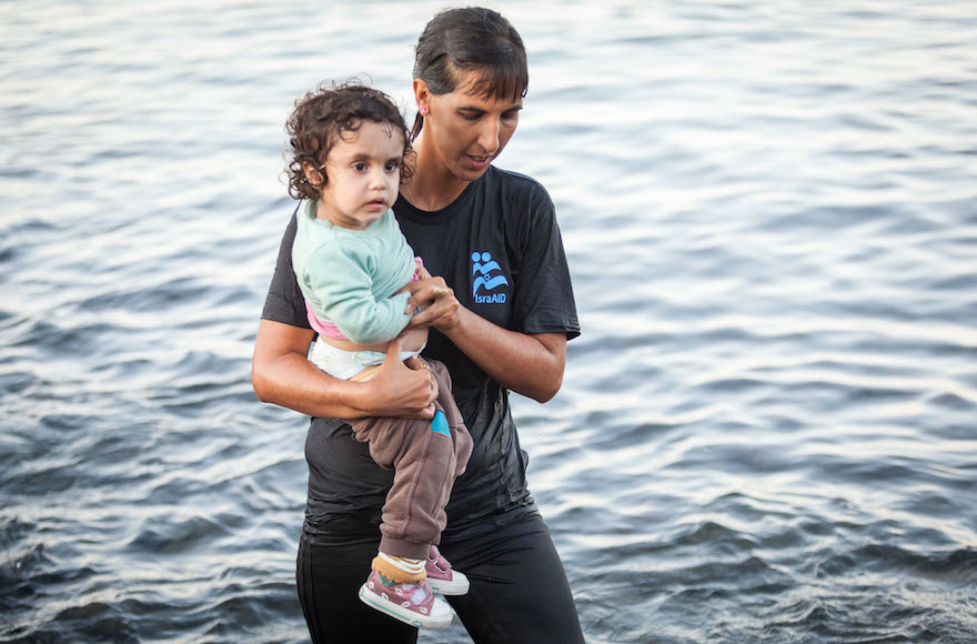 Tali Shaltiel, an Israeli physician, taking a Syrian child from a dinghy that arrived at a beach on the Greek island of Lesbos. Photo: Boaz Arad/IsraAid