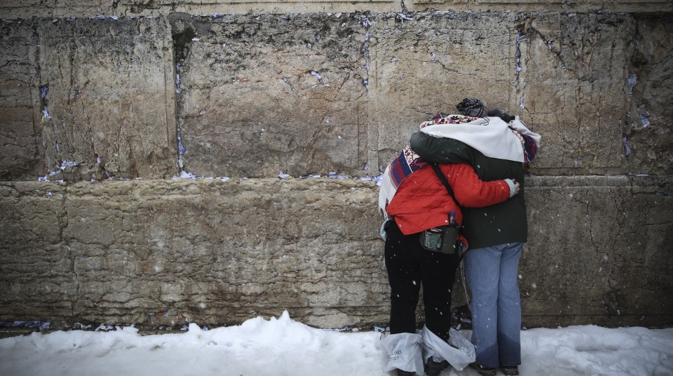 Worshipers pray amid snowfall at the Western Wall. Photo: Hadas Parush / Flash90