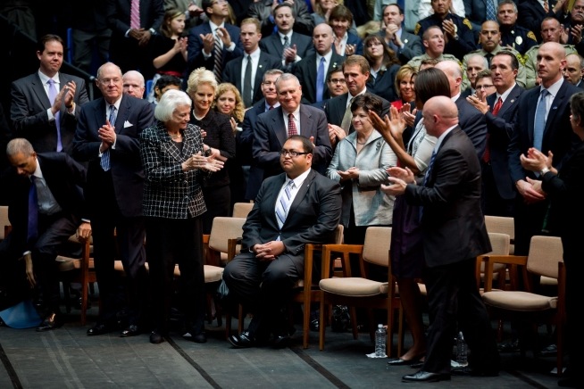 Daniel Hernandez receives a standing ovation at a memorial event dedicated to the victims of the Tucson shooting. First Lady Michelle Obama and Gabrielle Giffords’ husband, astronaut Mark Kelly, stand next to him. Photo: Chuck Kennedy / White House / Wikimedia