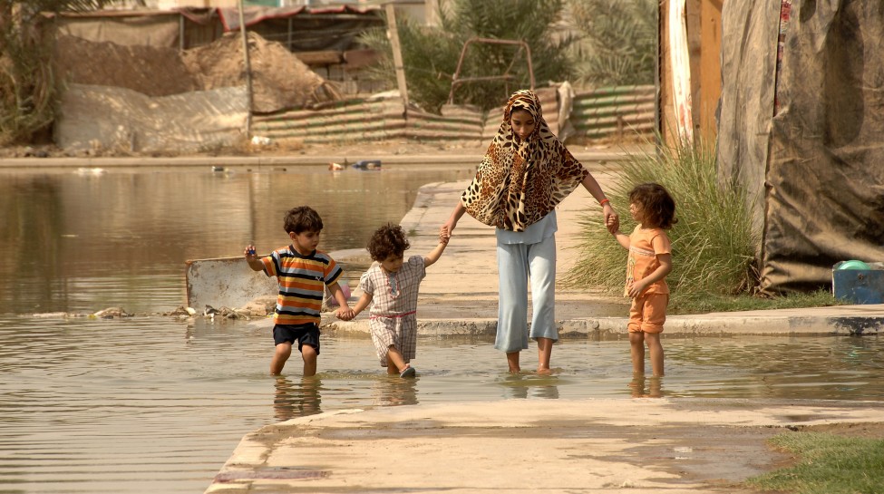 A family in Baghdad makes its way through streets flooded by a water main break. Photo: Spc. Charles Gill / flickr