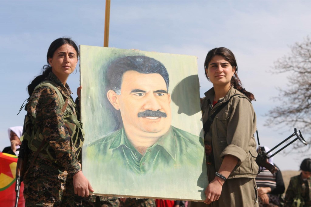 Soldiers from the YBŞ and PKK hold up a painting of their political leader, Abdullah Öcalan. Photo: Kurdish Struggle / flickr