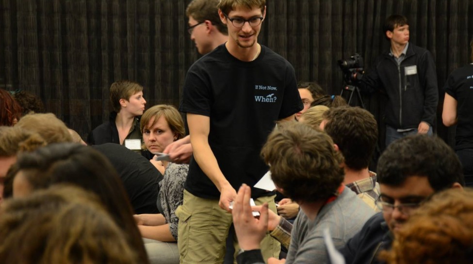 An Open Hillel member hands out materials at a plenary session. Photo: Gili Getz