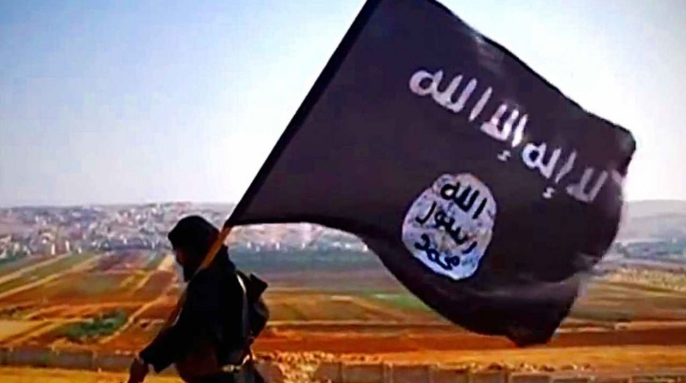 A member of Islamic State carries the group’s flag. Photo: VOA / Wikimedia